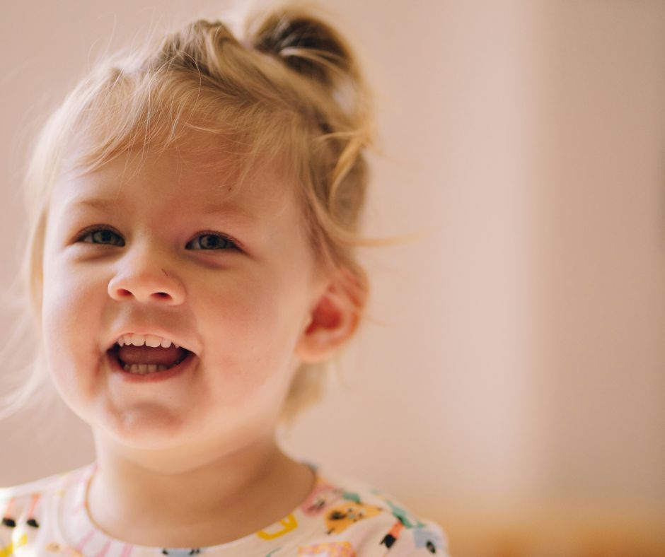 A toddler girl smiling.