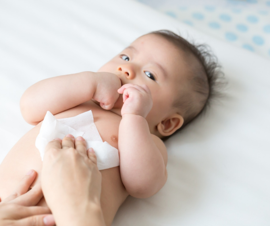 An infant has his belly cleaned with a baby wipe