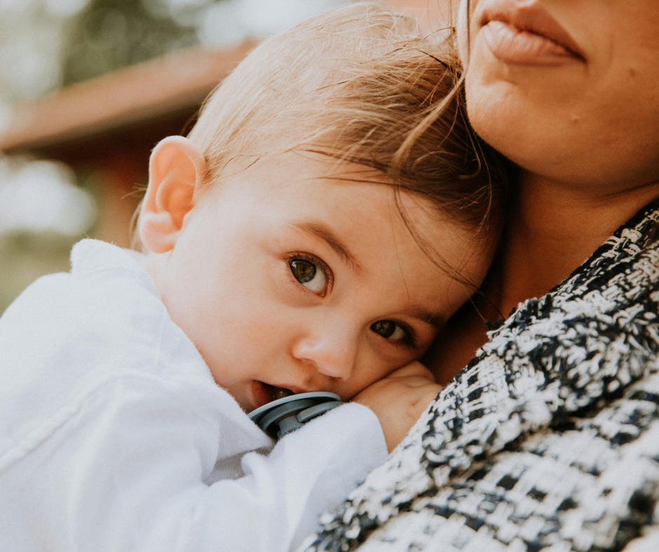 A baby snuggles against her mother's chest.