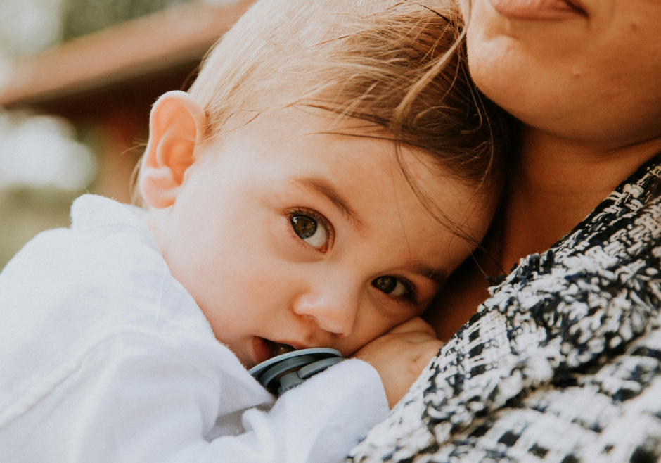 A baby snuggles against her mother's chest.