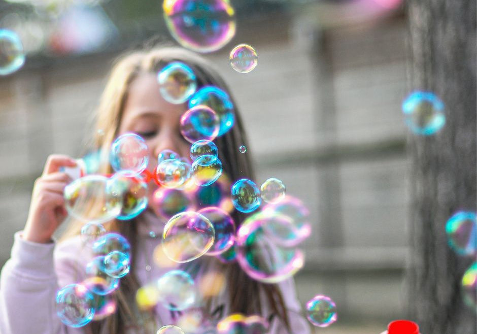 A toddler girl blows bubbles