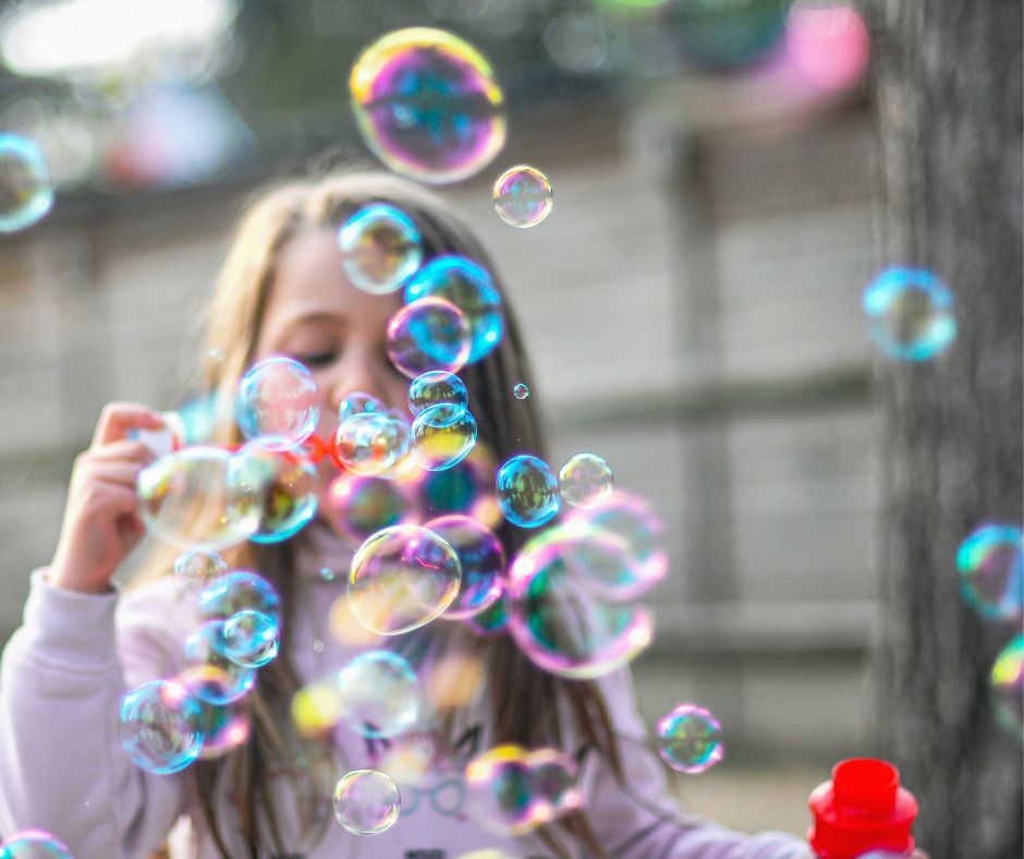 A toddler girl blows bubbles