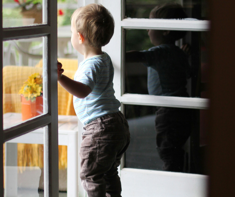 A toddler boy peeks outside during spring.