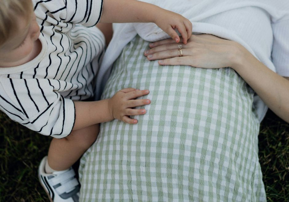 A toddler boy touches his pregnant mom's belly.
