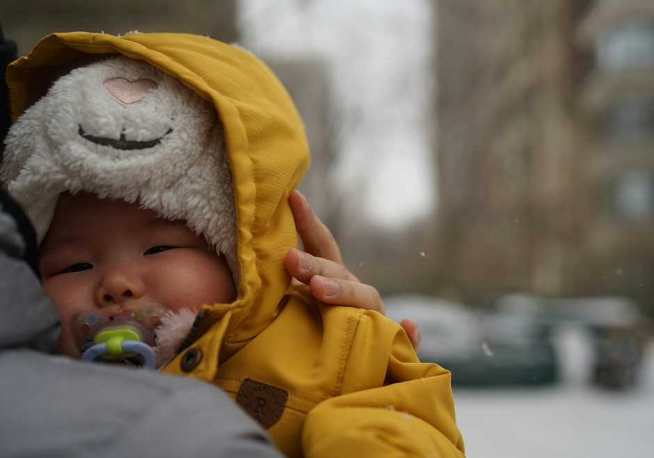 A sick baby all bundled up for cold weather snuggles on their parent's shoulder