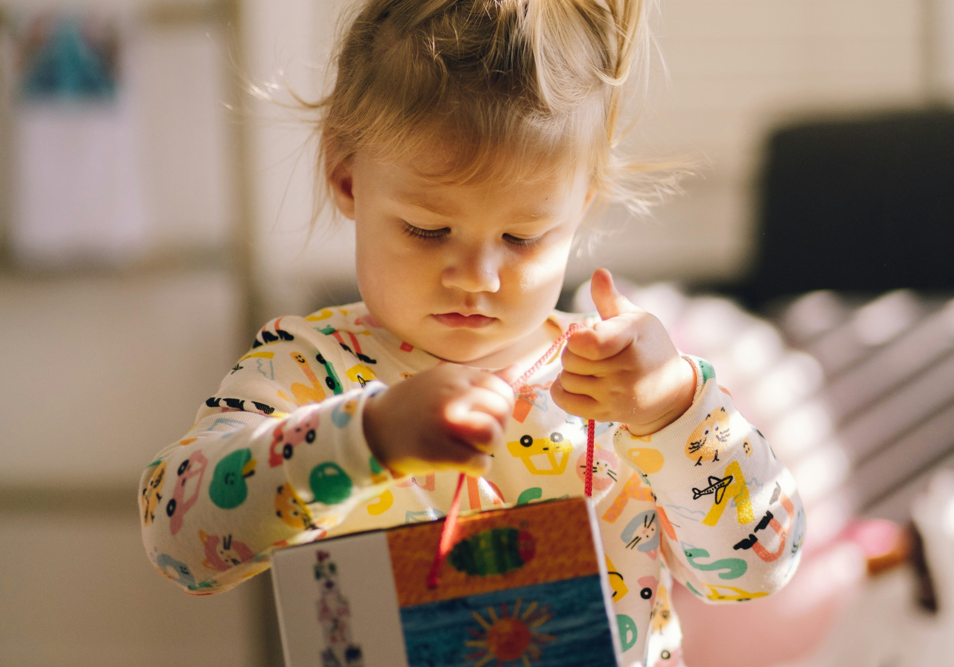 An adorable toddler girl playing with a book.
